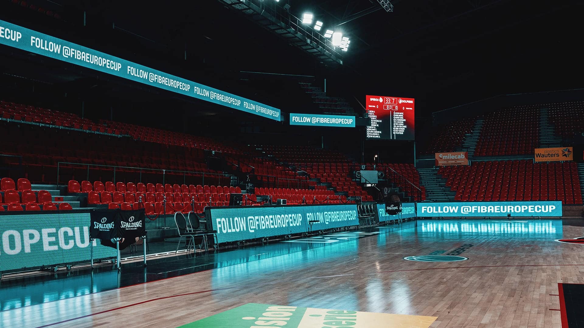 a basketball court with a wooden floor and red seats